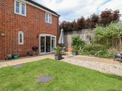 a brick house with a garden and an umbrella at 1 Coconut Cottage, Long Melford in Long Melford