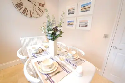 a white dining room table with a vase of flowers at High Tide, Crabbe Street, Aldeburgh in Aldeburgh
