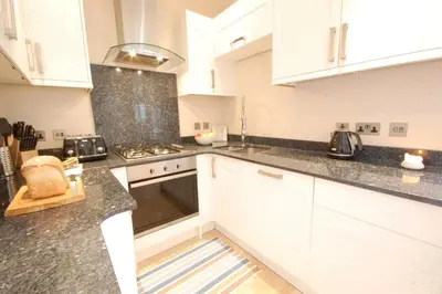a kitchen with white cabinets and granite counter tops at High Tide, Crabbe Street, Aldeburgh in Aldeburgh