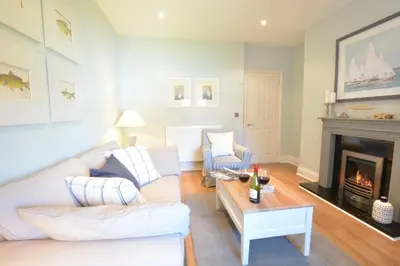 a living room with a white couch and a fireplace at High Tide, Crabbe Street, Aldeburgh in Aldeburgh