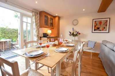 a dining room and living room with a table and chairs at Three Chantry Barns, Orford in Orford