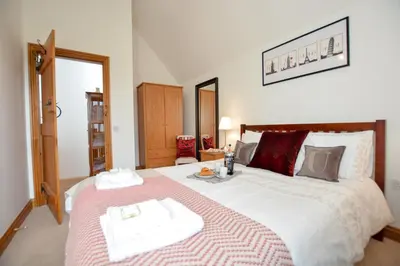 a bedroom with a large bed with two towels on it at Three Chantry Barns, Orford in Orford