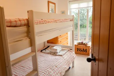 a bedroom with two bunk beds and a window at Three Chantry Barns, Orford in Orford