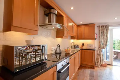 a kitchen with wooden cabinets and a stove top oven at Three Chantry Barns, Orford in Orford