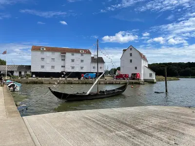 a boat sitting in the water next to a building at Beresford House in Woodbridge