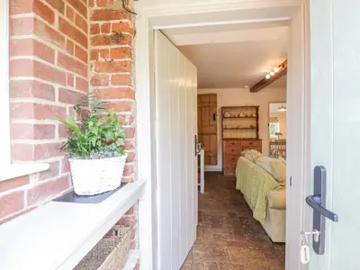 an open door to a room with a brick wall at Shoemakers Cottage, Friston in Friston