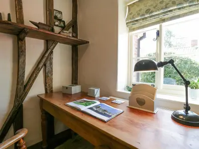 a desk with a lamp and a book on it at Shoemakers Cottage, Friston in Friston