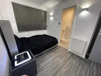 a small bedroom with a black bed and a window at Newly refurbished modern 2 bedroom flat in Trimley Heath