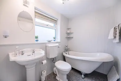 a white bathroom with a sink and a tub and a toilet at The Apartment at Clare House, Aldeburgh in Aldeburgh