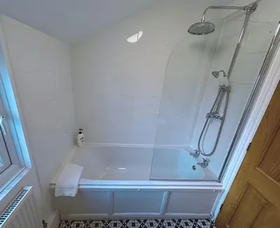 a bathroom with a tub with a shower at Quaint 2 bed Cottage in the Heart of Cambridge in Cambridge