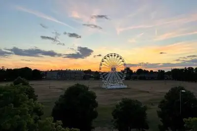 a ferris wheel in a field with a sunset at Quaint 2 bed Cottage in the Heart of Cambridge in Cambridge