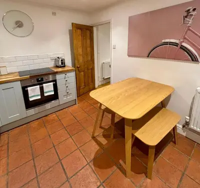 a kitchen with a wooden table and a stove at Quaint 2 bed Cottage in the Heart of Cambridge in Cambridge