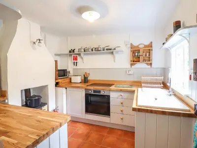 a kitchen with a sink and a stove top oven at Warren Cottage in Leavenheath
