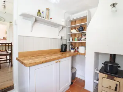 a kitchen with white cabinets and a counter top at Warren Cottage in Leavenheath