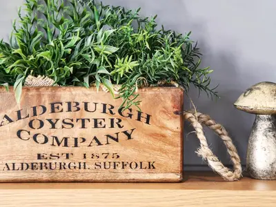 a wooden sign sitting on a table with plants at Alde Lodge by The Suffolk Cottage Collection in Aldeburgh