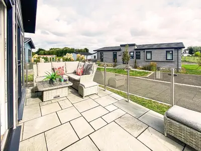 an outdoor patio with a couch and a table at Alde Lodge by The Suffolk Cottage Collection in Aldeburgh