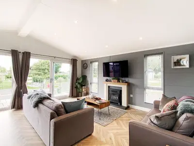 a living room with two couches and a fireplace at Alde Lodge by The Suffolk Cottage Collection in Aldeburgh