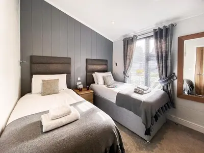 a bedroom with two beds and a window at Alde Lodge by The Suffolk Cottage Collection in Aldeburgh