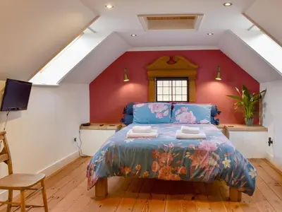 a bedroom with a king sized bed in a attic at The Old Butcher's Shop in Wereham