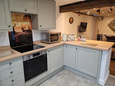 a kitchen with white cabinets and a counter with a microwave at Middle Tree, ideal modern cottage in Alburgh