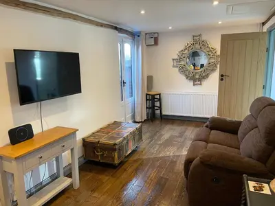 a living room with a couch and a flat screen tv at Middle Tree, ideal modern cottage in Alburgh