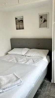 a white bed with two pillows on top of it at Cheerful 3 bedroom Townhouse with free parking. in Billericay