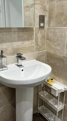 a bathroom with a white sink and a mirror at Cheerful 3 bedroom Townhouse with free parking. in Billericay