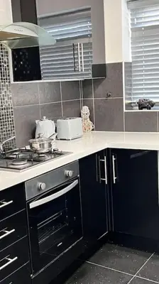 a kitchen with black cabinets and a stove top oven at Cheerful 3 bedroom Townhouse with free parking. in Billericay