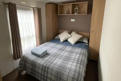 a small bedroom with a bed with pillows and a window at Caravan - Sleeps 10 - Pet friendly - Parking in Clacton-on-Sea