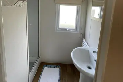 a white bathroom with a sink and a window at Caravan - Sleeps 10 - Pet friendly - Parking in Clacton-on-Sea