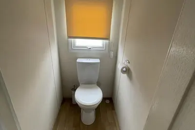 a small bathroom with a white toilet with a window at Caravan - Sleeps 10 - Pet friendly - Parking in Clacton-on-Sea