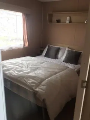 a large white bed in a room with a window at Summer plot 8 in Jaywick Sands