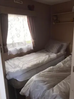 two beds in a small room with a window at Summer plot 8 in Jaywick Sands