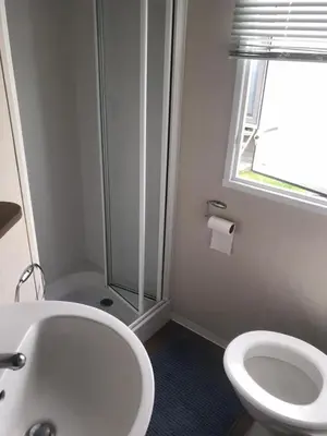 a bathroom with a shower and a toilet and a sink at Summer plot 8 in Jaywick Sands