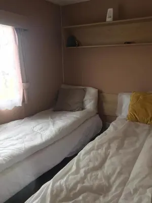 two beds in a small room with a window at Summer plot 8 in Jaywick Sands