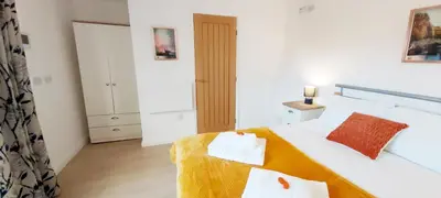 a bedroom with a large white bed with orange pillows at Modern, well located en-suite rooms with parking - Orbitat Accommodations in Cambridge