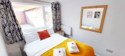 a small bedroom with a bed with towels on it at Modern, well located en-suite rooms with parking - Orbitat Accommodations in Cambridge