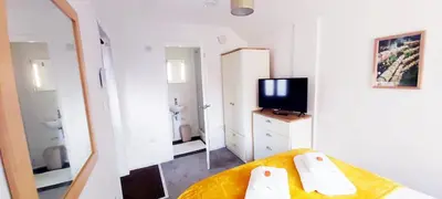a room with a bed and a tv and a mirror at Modern, well located en-suite rooms with parking - Orbitat Accommodations in Cambridge