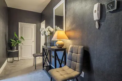 a living room with a chair and a mirror at Crown Street in Bury Saint Edmunds