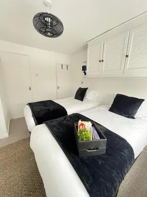 two beds in a hotel room with a tray on the bed at Cambridge Stay Cozy home with Wi-Fi, Parking Perfect for 2 in Cherry Hinton