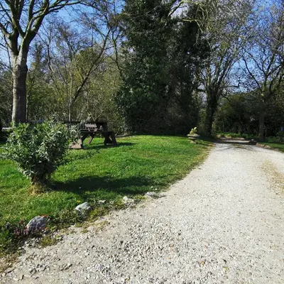a gravel road next to a park with a bench at Meadow Farm Cottage in Norwich