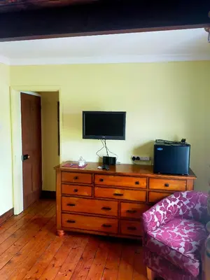 a living room with a wooden dresser with a television on it at Meadow Farm Cottage in Norwich