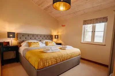 a bedroom with a large bed with yellow sheets and a window at Beautiful Cottage in Bredfield near to Woodbridge on the Suffolk Coast in Bredfield