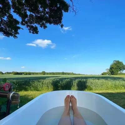 a woman laying in a bath tub with her feet in it at Beautiful Cottage in Bredfield near to Woodbridge on the Suffolk Coast in Bredfield