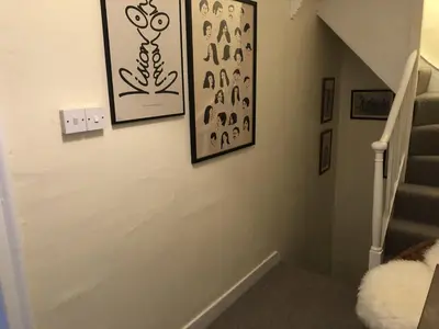 a hallway with two pictures on the wall and a staircase at Arts House in Harwich