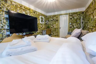 a bedroom with a large white bed and a tv at Deluxe 4 or 5 Bed House with Hot Tub, Cinema Room Sleeps 15 in Saffron Walden
