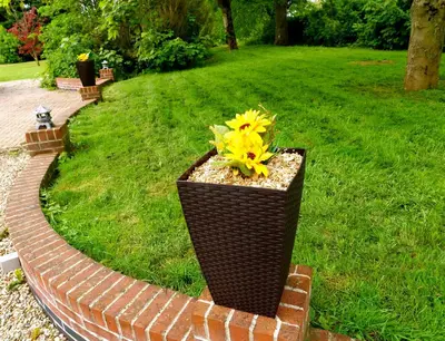 a planter with a yellow flower on a brick path at Deluxe 4 or 5 Bed House with Hot Tub, Cinema Room Sleeps 15 in Saffron Walden