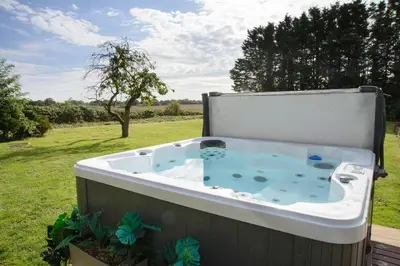 a jacuzzi tub sitting in a yard at Deluxe 4 or 5 Bed House with Hot Tub, Cinema Room Sleeps 15 in Saffron Walden