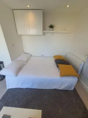 a bedroom with a large white bed with yellow pillows at The Tiny Sea Gem in Jaywick Sands