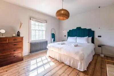 a bedroom with a large bed and a wooden dresser at The Limes, Benhall in Saxmundham